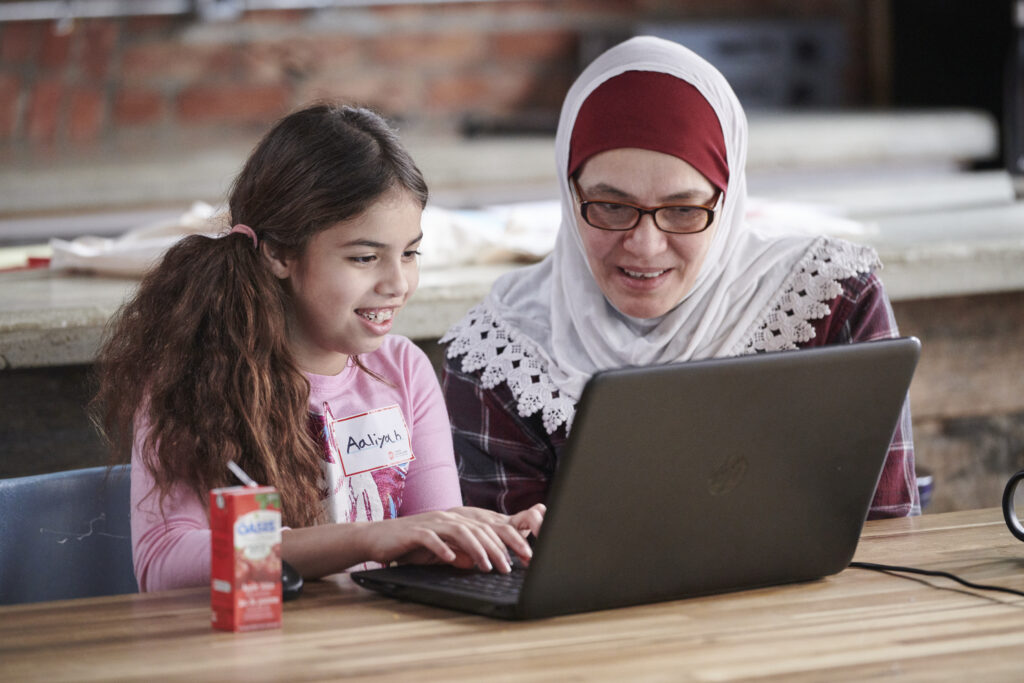 Mother and daughter typing on computer