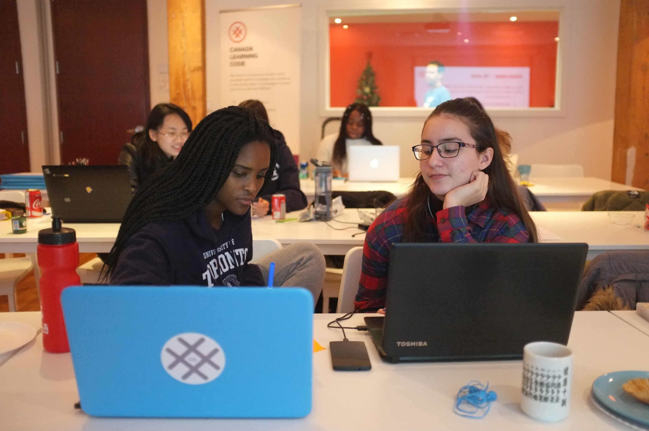 Two teen girls in front of their laptops working on their project