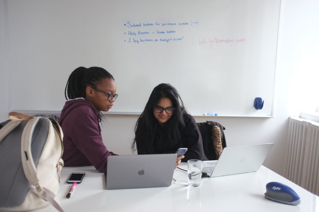 Two teen girls looking at their laptops