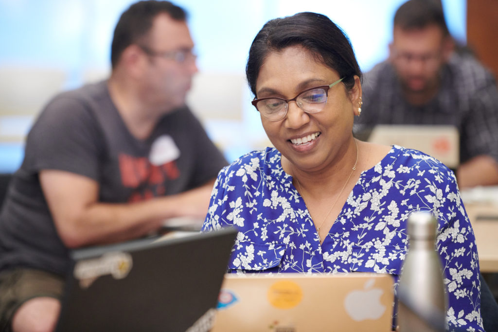 Female-identified person looking at their laptop and smiling