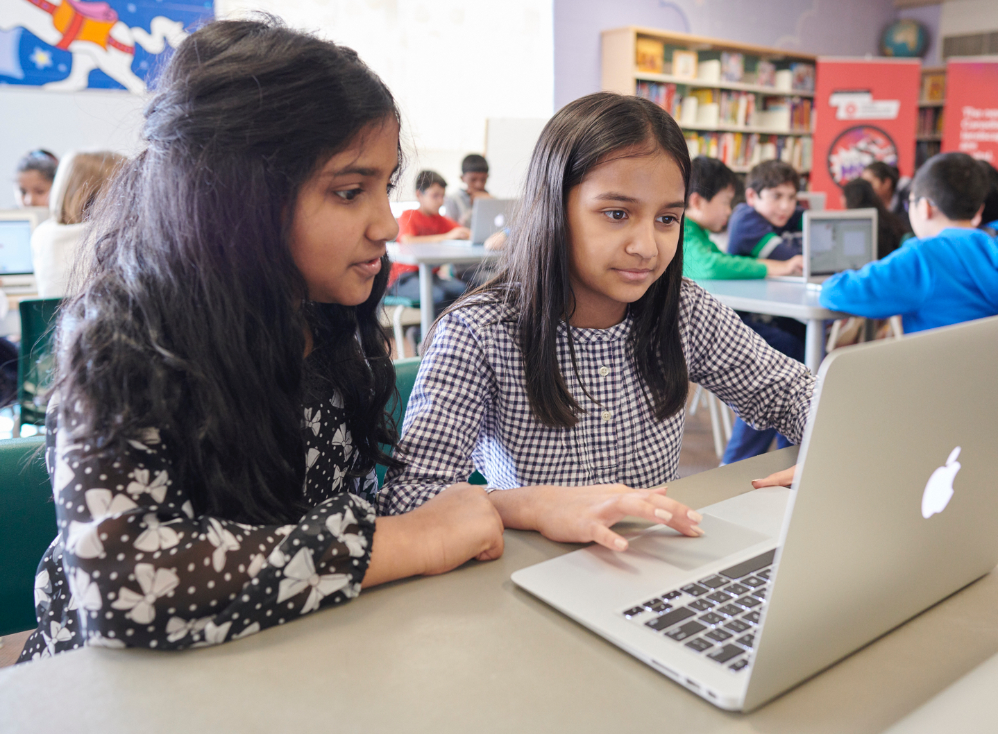 two girls sharing a laptop