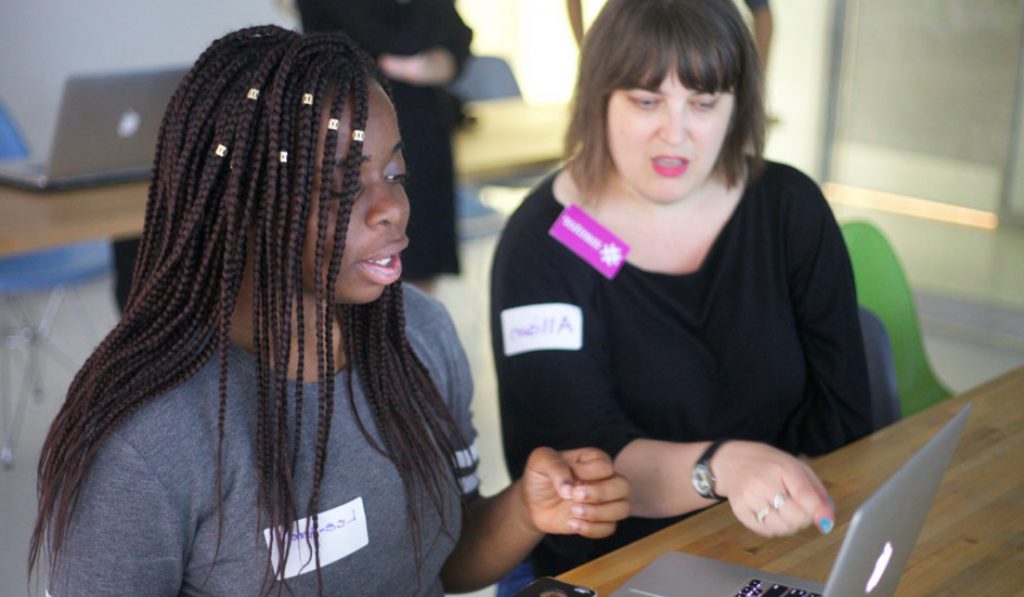 a learner looking and a mentor pointing to the laptop