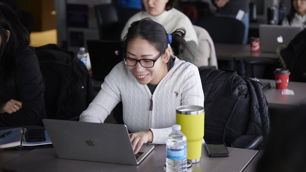 Woman coding on laptop in class